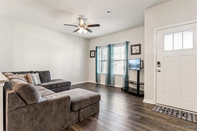 Living area with dark wood finished floors, baseboards, and a ceiling fan | Image 12