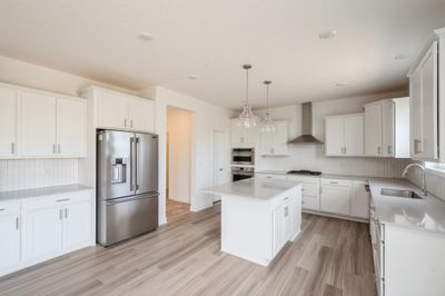 (Photo of an inventory home, actual homes finishes will vary) Modern and functional, the kitchen has ample cabinet space, gourmet kitchen appliances, quartz countertops, undercabinet lighting and beautiful luxury vinyl plank floors for easy cleaning. | Image 3