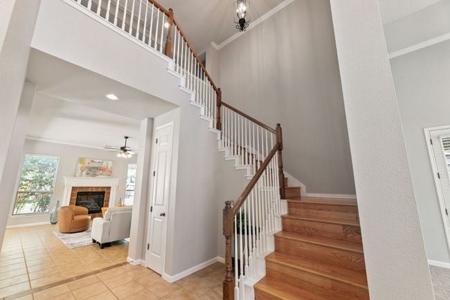 Stairs with ceiling fan, a tile fireplace, tile patterned floors, and ornamental molding | Image 6
