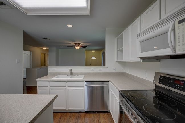 Kitchen featuring stainless steel appliances, a sink, a peninsula, and white cabinets | Image 21