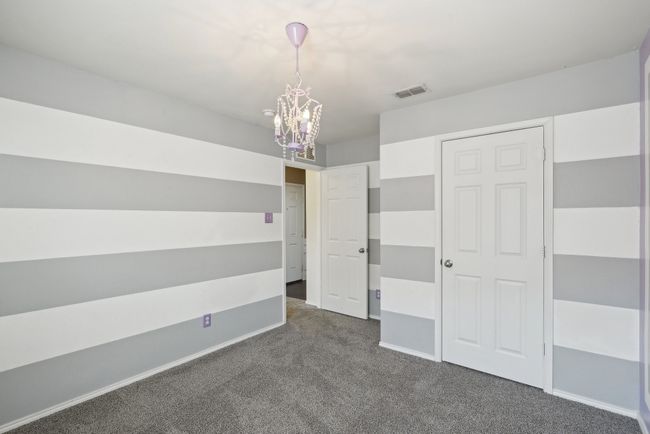 Unfurnished bedroom with baseboards, a notable chandelier, and dark carpet | Image 19