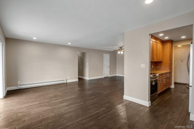 Unfurnished living room featuring baseboards, ceiling fan, dark wood-style floors, baseboard heating, and recessed lighting | Image 9