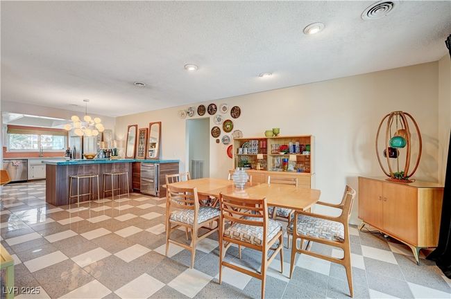 Dining room featuring visible vents, a notable chandelier, a textured ceiling, and light floors | Image 9