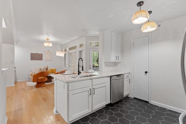 Kitchen featuring a sink, stainless steel dishwasher, a peninsula, white cabinetry, and hanging light fixtures | Image 8