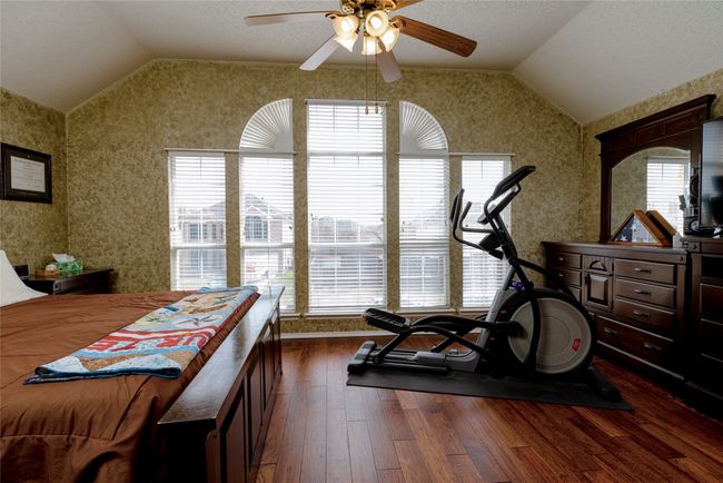 Exercise area featuring lofted ceiling, dark wood-style floors, wallpapered walls, and ceiling fan | Image 23