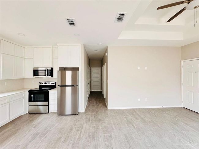 Kitchen featuring appliances with stainless steel finishes, ceiling fan, white cabinetry, and light wood-type flooring | Image 4