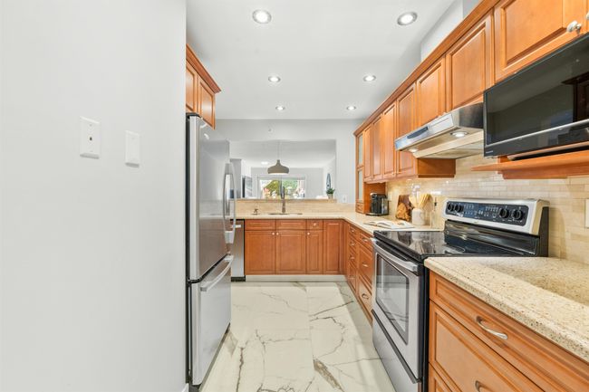 Kitchen featuring marble finish floor, stainless steel appliances, recessed lighting, decorative backsplash, and under cabinet range hood | Image 9