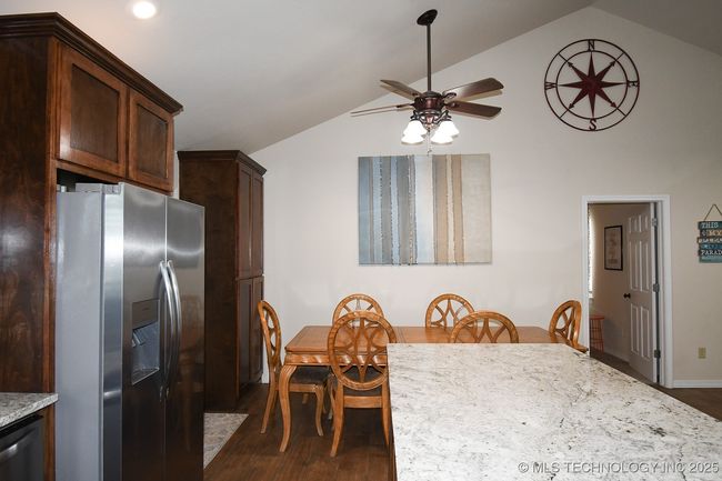Dining room with a ceiling fan, dark wood-style floors, vaulted ceiling, and baseboards | Image 14