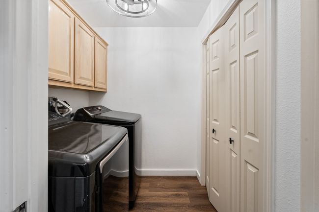 Clothes washing area with dark hardwood / wood-style flooring, washing machine and dryer, and cabinets | Image 21