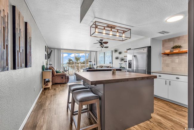 Kitchen with open shelves, stainless steel refrigerator with ice dispenser, light wood finished floors, and butcher block counters | Image 13