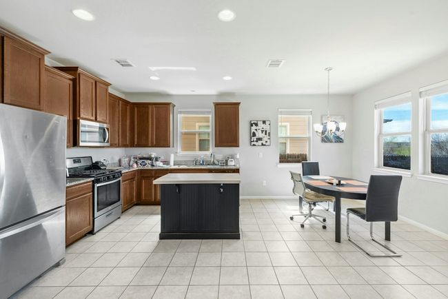 Kitchen with a chandelier, light tile patterned floors, appliances with stainless steel finishes, and light countertops | Image 8