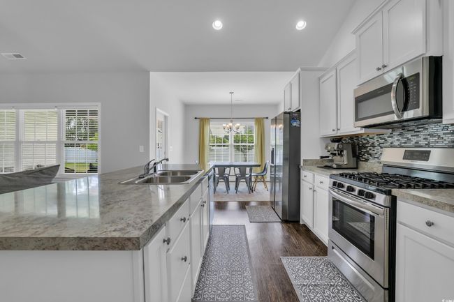 Kitchen with white cabinets, an inviting chandelier, a sink, and appliances with stainless steel finishes | Image 23