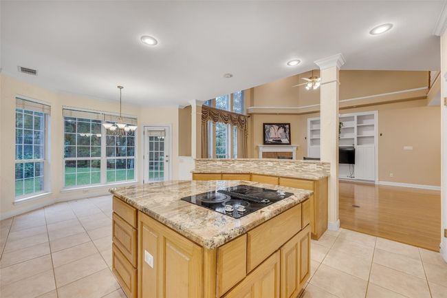 Kitchen featuring black electric cooktop, ornate columns, light tile patterned flooring, a kitchen island, and recessed lighting | Image 18