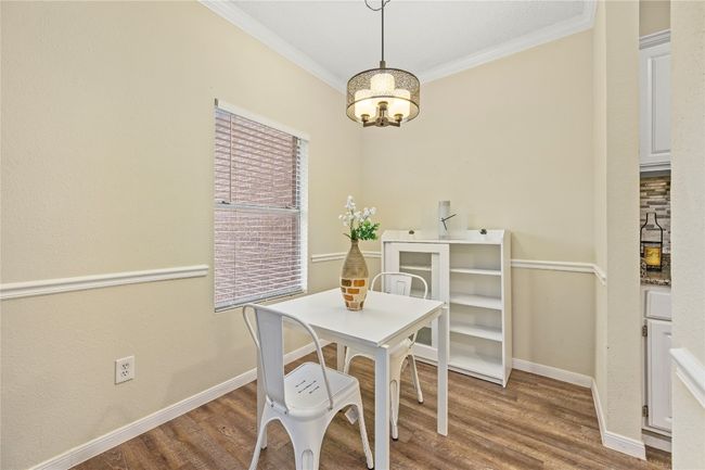 Dining room with baseboards, crown molding, a chandelier, and wood finished floors | Image 4