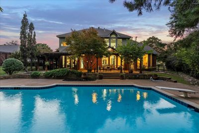 Pool at dusk featuring a diving board and a patio area | Image 2