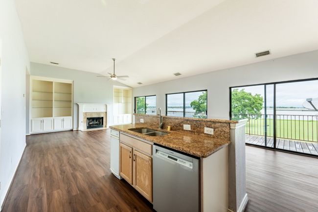 Kitchen with a ceiling fan, a fireplace with flush hearth, dishwasher, open floor plan, and dark wood-style flooring | Image 12