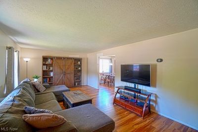 Living room with a barn door, a textured ceiling, and wood-type flooring | Image 3