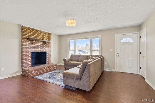 Living area featuring visible vents, a textured ceiling, baseboards, and wood finished floors | Image 15