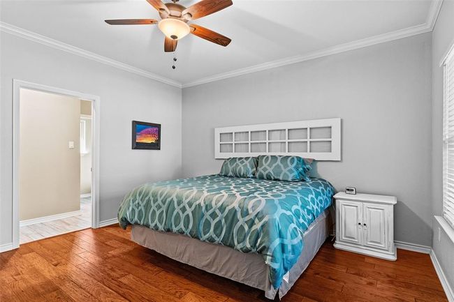 Bedroom with wood-type flooring, ceiling fan, and ornamental molding | Image 8