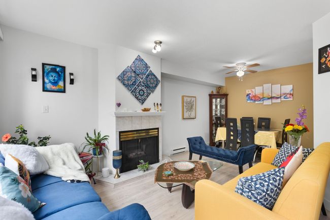Living room featuring wood finished floors, a fireplace, a baseboard radiator, and ceiling fan | Image 6