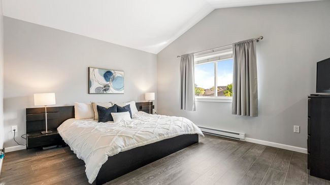Bedroom featuring baseboards, baseboard heating, wood finished floors, and vaulted ceiling | Image 15