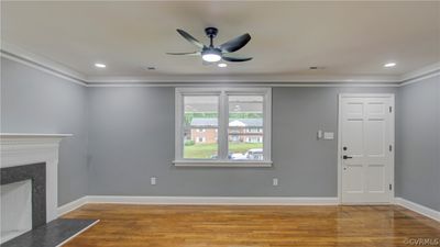 Unfurnished living room featuring a fireplace, ceiling fan, hardwood / wood-style floors, and crown molding | Image 2