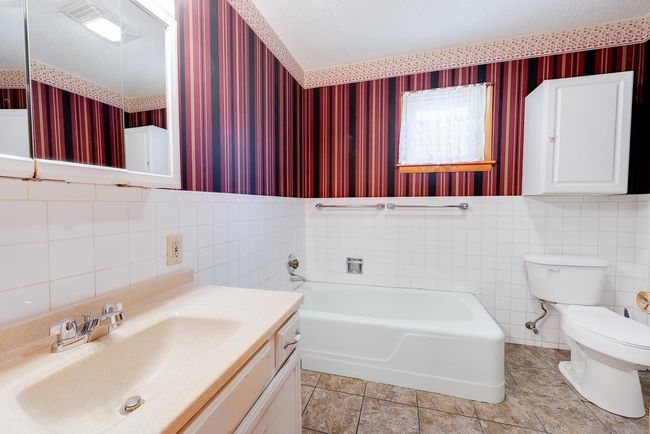 Bathroom featuring wallpapered walls, toilet, a bath, vanity, and tile walls | Image 14