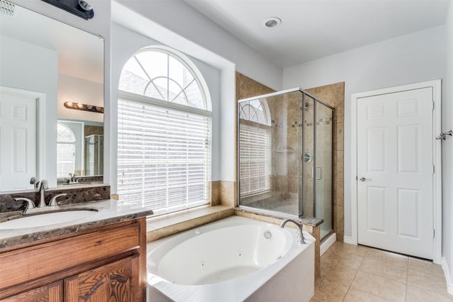 Full bath with a whirlpool tub, a stall shower, vanity, and healthy amount of natural light | Image 19
