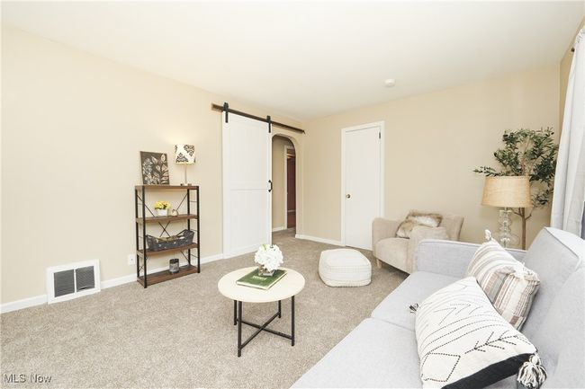 Living room with a barn door, arched walkways, light colored carpet, baseboards, and visible vents | Image 16