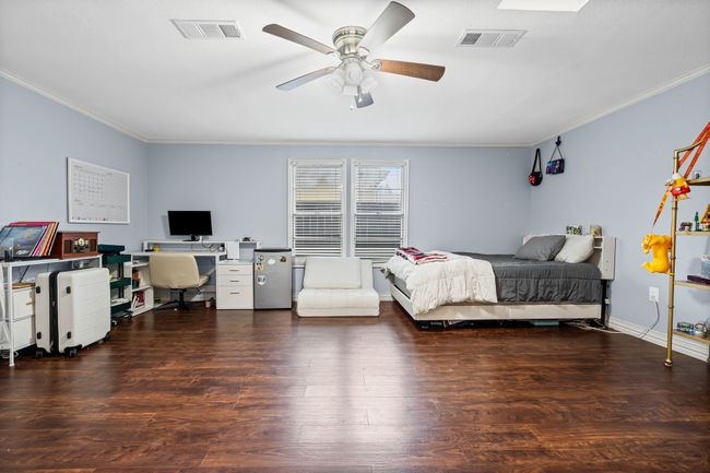 Bedroom with crown molding, an office area, wood finished floors, and a ceiling fan | Image 19