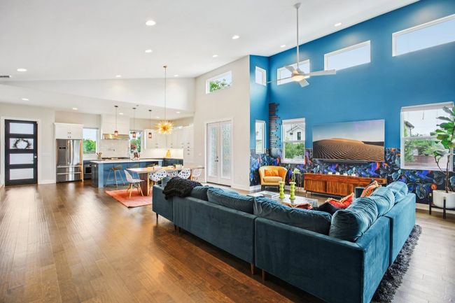 Living room featuring a towering ceiling, a ceiling fan, dark wood-style flooring, recessed lighting, and healthy amount of natural light | Image 10