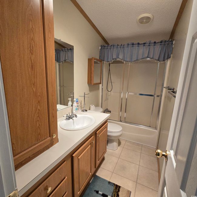 Full bathroom with tile patterned flooring, a textured ceiling, vanity, bath / shower combo with glass door, and crown molding | Image 30