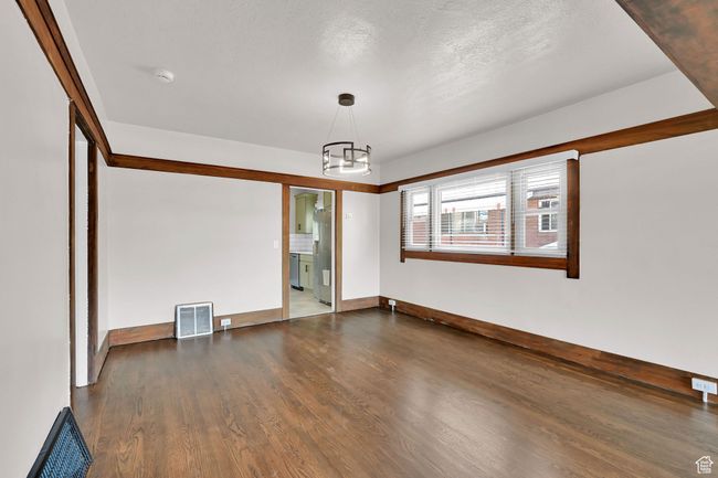 Spare room featuring wood finished floors, a chandelier, and baseboards | Image 9
