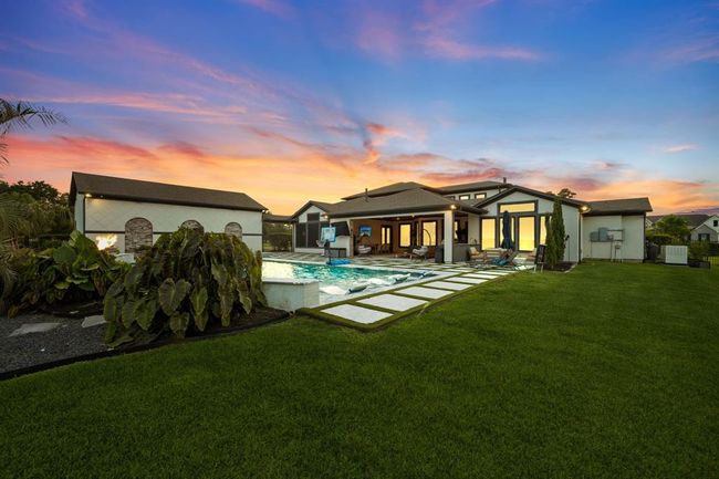 This stunning property features a modern home with a spacious backyard, complete with a swimming pool, covered patio, and lush landscaping. The sunset view adds a warm, inviting ambiance. Perfect for outdoor entertaining and relaxation. | Image 44
