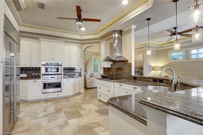 Kitchen with appliances with stainless steel finishes, wall chimney range hood, ceiling fan, a sink, and visible vents | Image 18