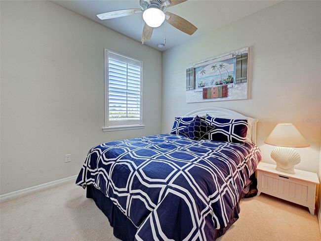 Guest bedroom features a ceiling fan and plantation shutters | Image 37