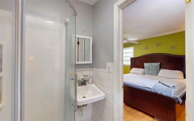 Bathroom featuring a sink, tile walls, a ceiling fan, wainscoting, and a shower | Image 30