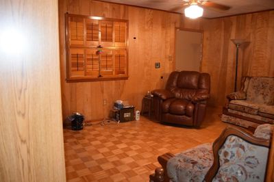 Living room featuring ceiling fan, wooden walls, and parquet floors | Image 3