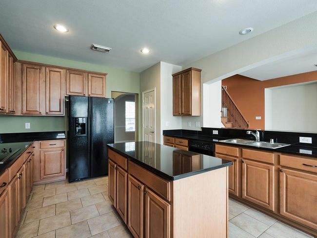 Kitchen featuring black appliances, a sink, light tile patterned floors, a kitchen island, and recessed lighting | Image 19