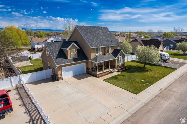 View of front of home with stucco siding, covered porch, a residential view, driveway, and a front lawn | Image 46