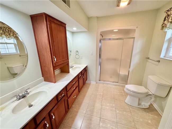 Master bath with ceramic tile floor, solid surface countertop, and walk-in shower. | Image 13