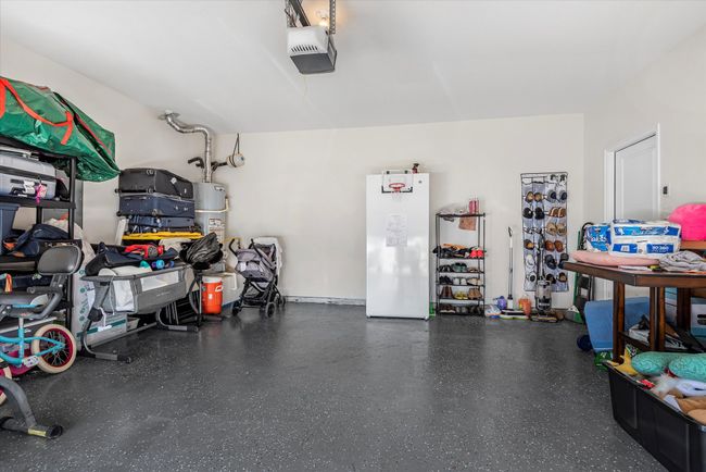 Garage with a garage door opener, freestanding refrigerator, and gas water heater | Image 31