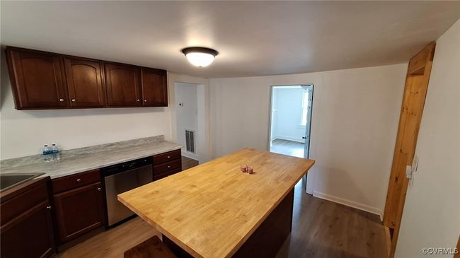 Kitchen with butcher block counters, dishwasher, visible vents, and dark wood-style floors | Image 16
