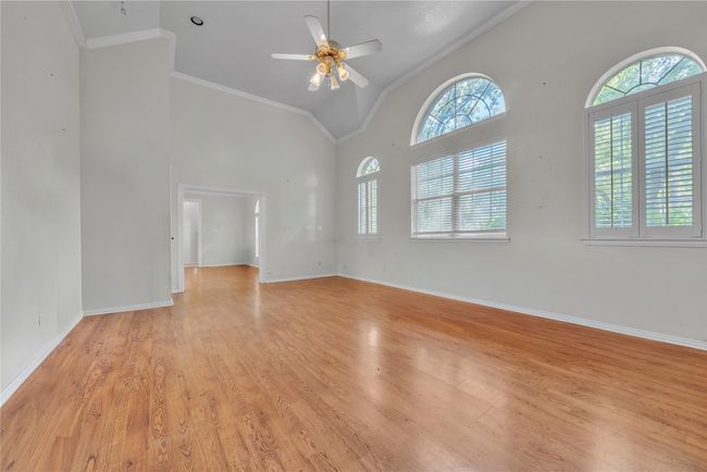 Spare room featuring ceiling fan, crown molding, light wood-type flooring, and high vaulted ceiling | Image 11