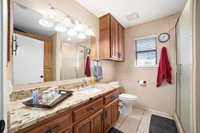 Bathroom with vanity, an enclosed shower, tile patterned floors, and toilet | Image 11