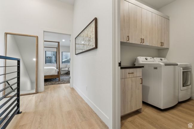 Laundry room featuring washer and clothes dryer, light wood-type flooring, and cabinets | Image 25