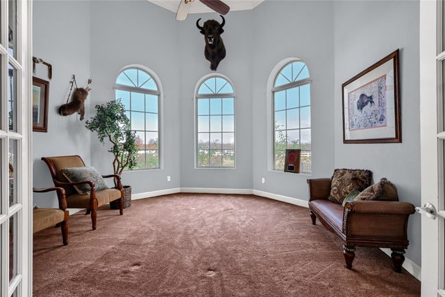 Sitting room with ceiling fan, french doors, carpet floors, and a high ceiling | Image 24