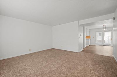 Unfurnished living room with a textured ceiling and carpet flooring | Image 3