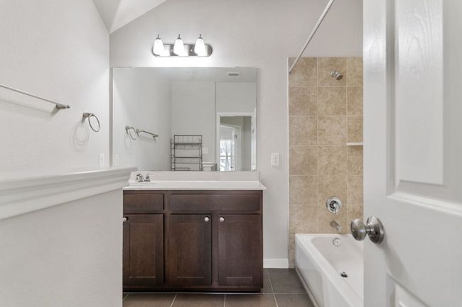 Full bath with tile patterned flooring, vanity, vaulted ceiling, shower / washtub combination, and visible vents | Image 31