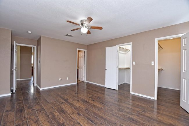 Unfurnished bedroom featuring a spacious closet, wood finished floors, and baseboards | Image 16